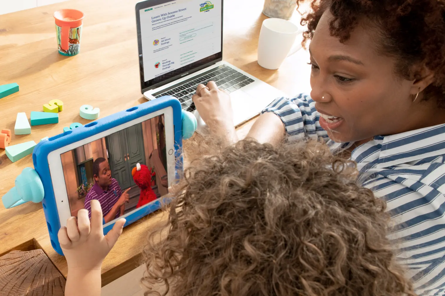 Grown up with Grown-Up Guide and child playing with Learn With Sesame Street app