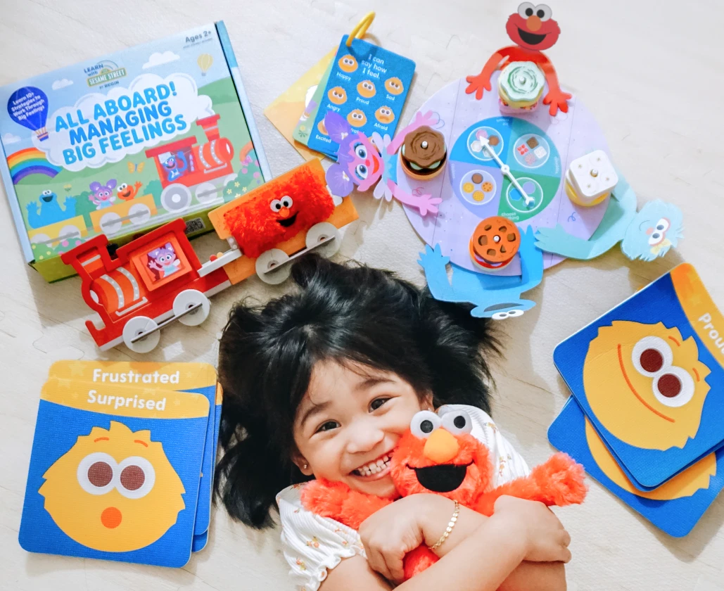Child playing with Learn With Sesame kits and hugging Elmo toy